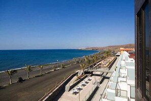 A coastal hotel with a view of the sea, a paved walkway, and a row of sun loungers. - R2 Bahía Design Hotel & Spa Wellness - Adults Only (Tuineje)