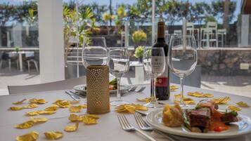 Una mesa servida para una comida, con copas de vino, una botella y un plato de comida.