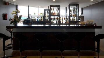 A bar area with a counter, multiple bottles, and bar stools.
