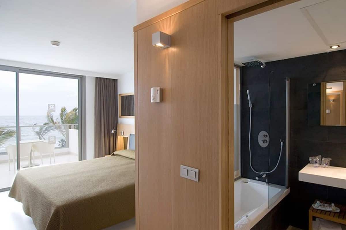 Une chambre d’hôtel moderne avec un balcon, une douche et un lit.