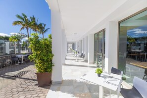 A modern outdoor patio area with tables and chairs, palm trees, and a clear sky. - R2 Bahía Design Hotel & Spa Wellness - Adults Only (Tuineje)
