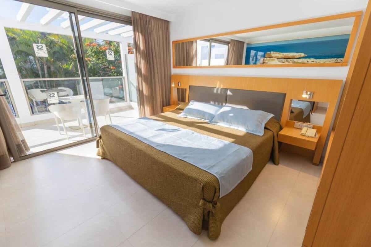 Une chambre d’hôtel avec un lit, une table de chevet, un miroir et une vue sur l’extérieur.