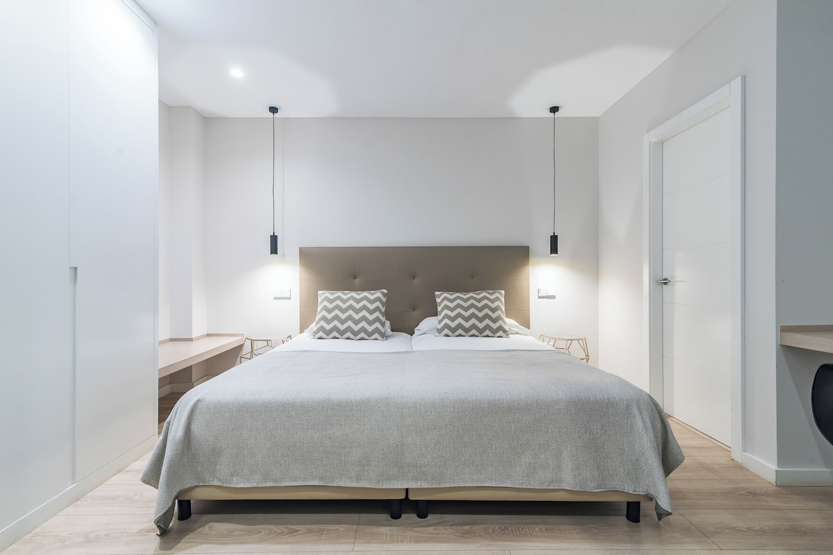 Un dormitorio moderno con una cama grande, dos mesitas de noche y un cabecero con iluminación integrada.
