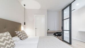 Een moderne slaapkamer met een groot bed, een bureau en een schuifdeur naar buiten.