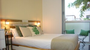 Ein modernes Schlafzimmer mit einem großen Bett, Nachttischen und Blick ins Freie.