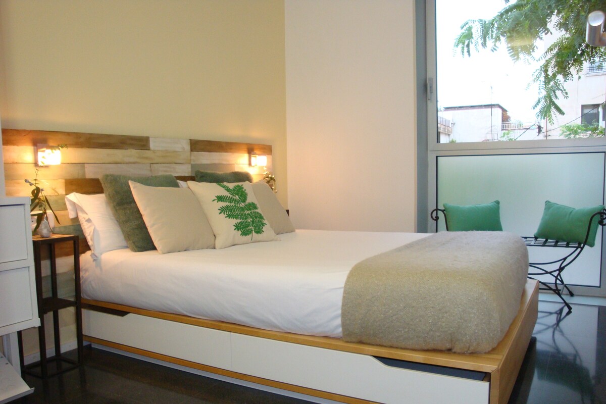 Ein modernes Schlafzimmer mit einem großen Bett, Nachttischen und Blick ins Freie.