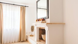 Un bagno moderno con un mobile vanitario bianco, uno specchio e un camino in mattoni a scomparsa.