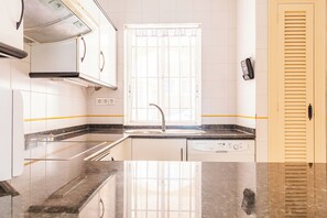 Eine moderne Küche mit weißen Schränken, einer Edelstahlspüle und einem eingebauten Geschirrspüler.
