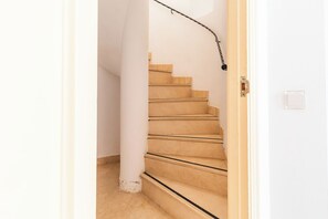 A staircase with beige steps and a handrail, leading to a door with a light switch. - Ona Las Lomas Village (Cartagena)