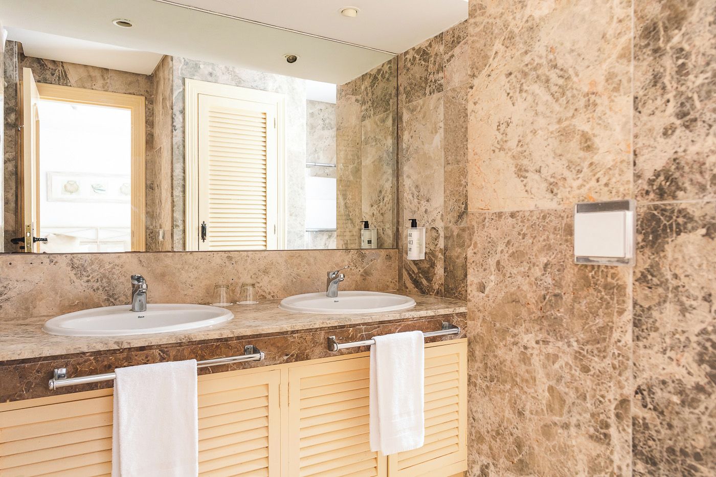 A bathroom with two sinks, a large mirror, and a towel rack.