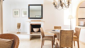 A modern dining area with wicker chairs, a round table, a fireplace, and a chandelier. - Ona Las Lomas Village (Cartagena)