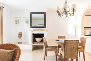 Una sala da pranzo moderna con sedie in vimini, un tavolo rotondo, un camino e un lampadario.