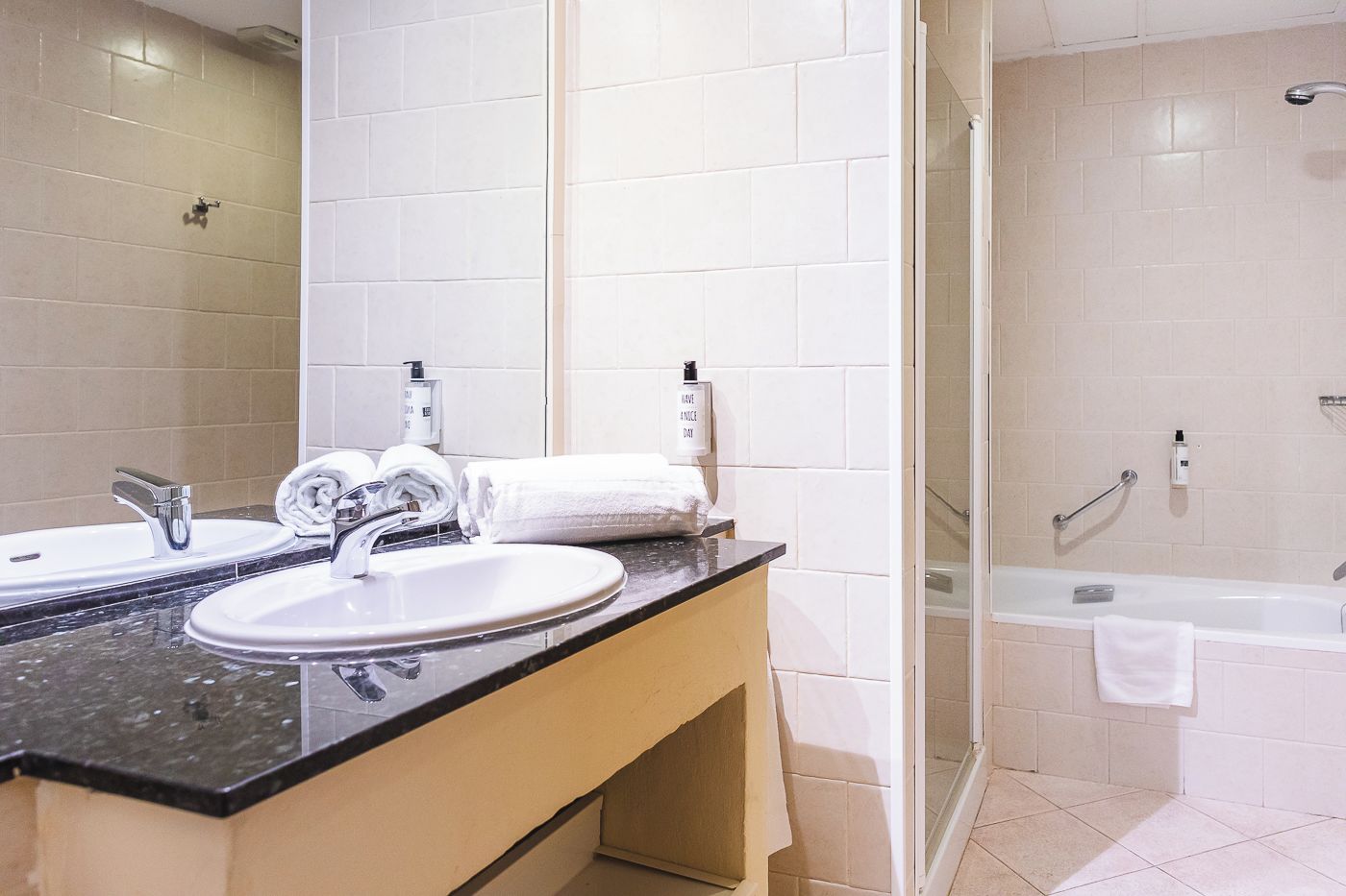 A modern bathroom with a double sink, a glass shower enclosure, and a bathtub.