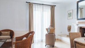A hotel room with wicker furniture, a fireplace, and a large window with curtains. - Ona Las Lomas Village (Cartagena)