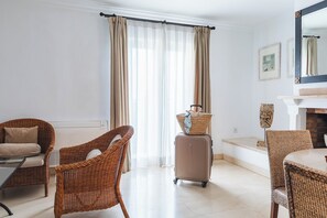Una camera d'albergo con mobili in vimini, un camino e un'ampia finestra con tende.