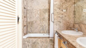 Une salle de bain avec une baignoire, deux lavabos et une douche.