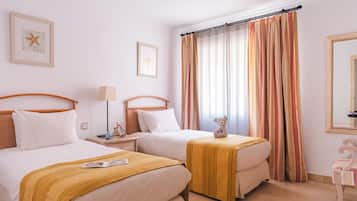 A hotel room with two beds, a nightstand with a lamp, a teddy bear, and a starfish decoration.