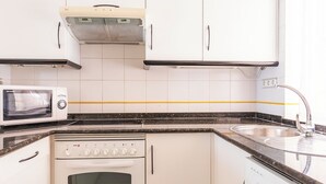 A kitchen with white cabinets, a microwave, an oven, and a dishwasher. - Ona Las Lomas Village (Cartagena)