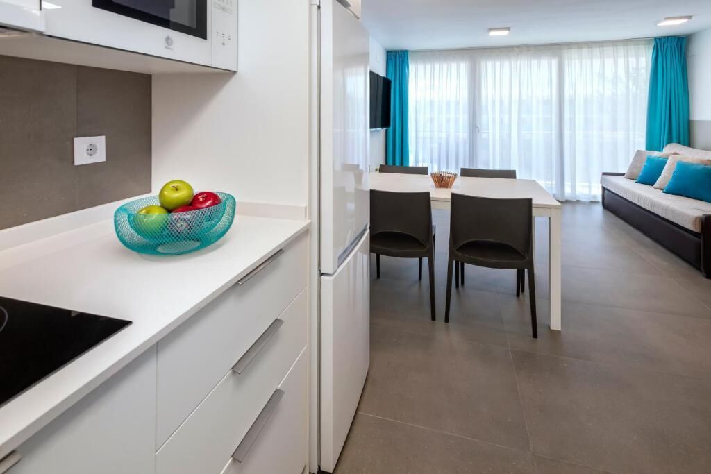 Eine moderne Küche mit weißer Arbeitsplatte, Obstschale, Einbau-Mikrowelle und Kühlschrank.