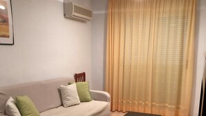 A living room with a beige sofa, a wooden chair, a black coffee table, and a large window with sheer curtains. - Acv-costa Marina Ii-1ª Linea Planta 10 Sur (Oropesa del Mar)