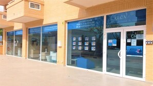 A building with a glass facade displaying property listings. - Acv-costa Marina Ii-1ª Linea Planta 10 Sur (Oropesa del Mar)