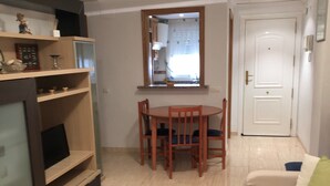 A living room with a TV, a dining table with chairs, a sofa, and a door. - Acv-costa Marina Ii-1ª Linea Planta 10 Sur (Oropesa del Mar)
