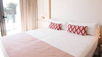 Una cama grande con una colcha rosa, almohadas blancas y un cabecero de madera.