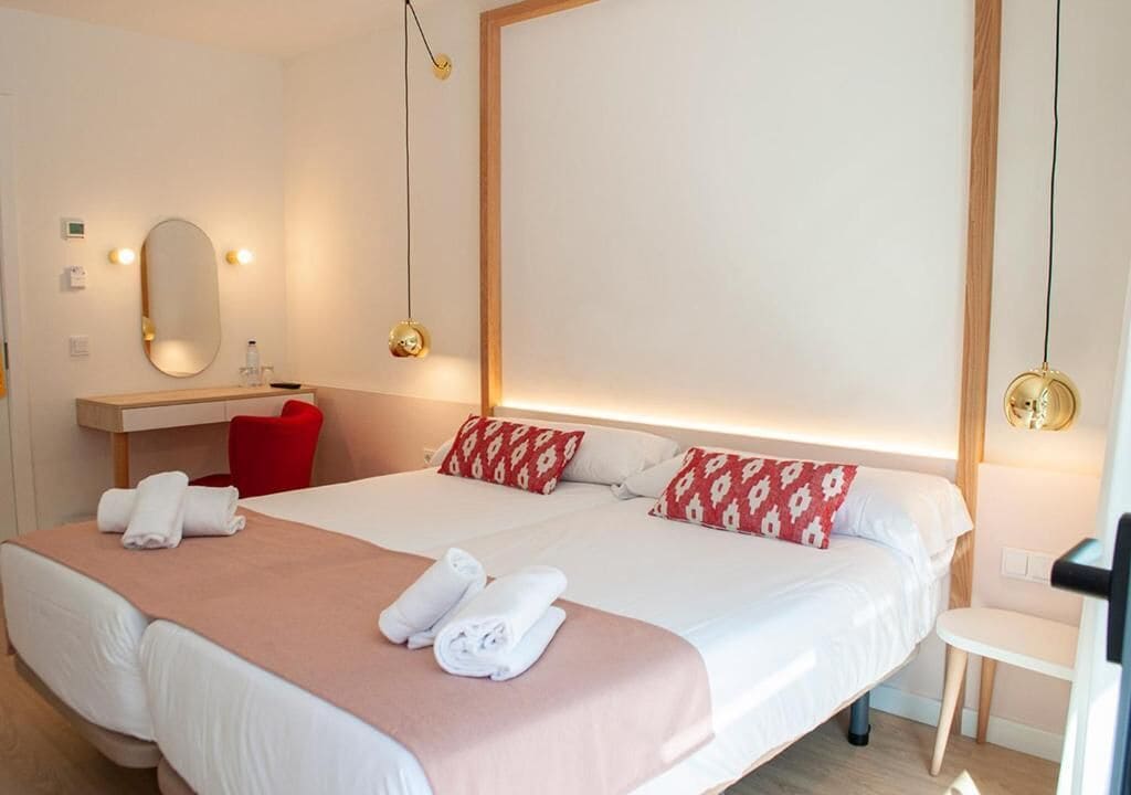 Una habitación de hotel con una cama doble, un escritorio, una silla y un espejo.