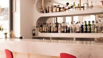 Eine moderne Bar mit zwei roten Barhocker, einer Marmorplatte und einer Auswahl an Spirituosenflaschen.