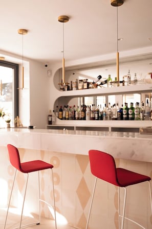 A modern bar area with two red bar stools, a marble countertop, and a variety of liquor bottles. - Sol i Vida Hotel & Restaurant (Manacor)