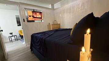 Une chambre à coucher avec un lit, un lustre et une bougie allumée sur une table de chevet.