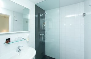 Un baño moderno con cabina de ducha de vidrio, un lavabo blanco y un espejo sobre él.