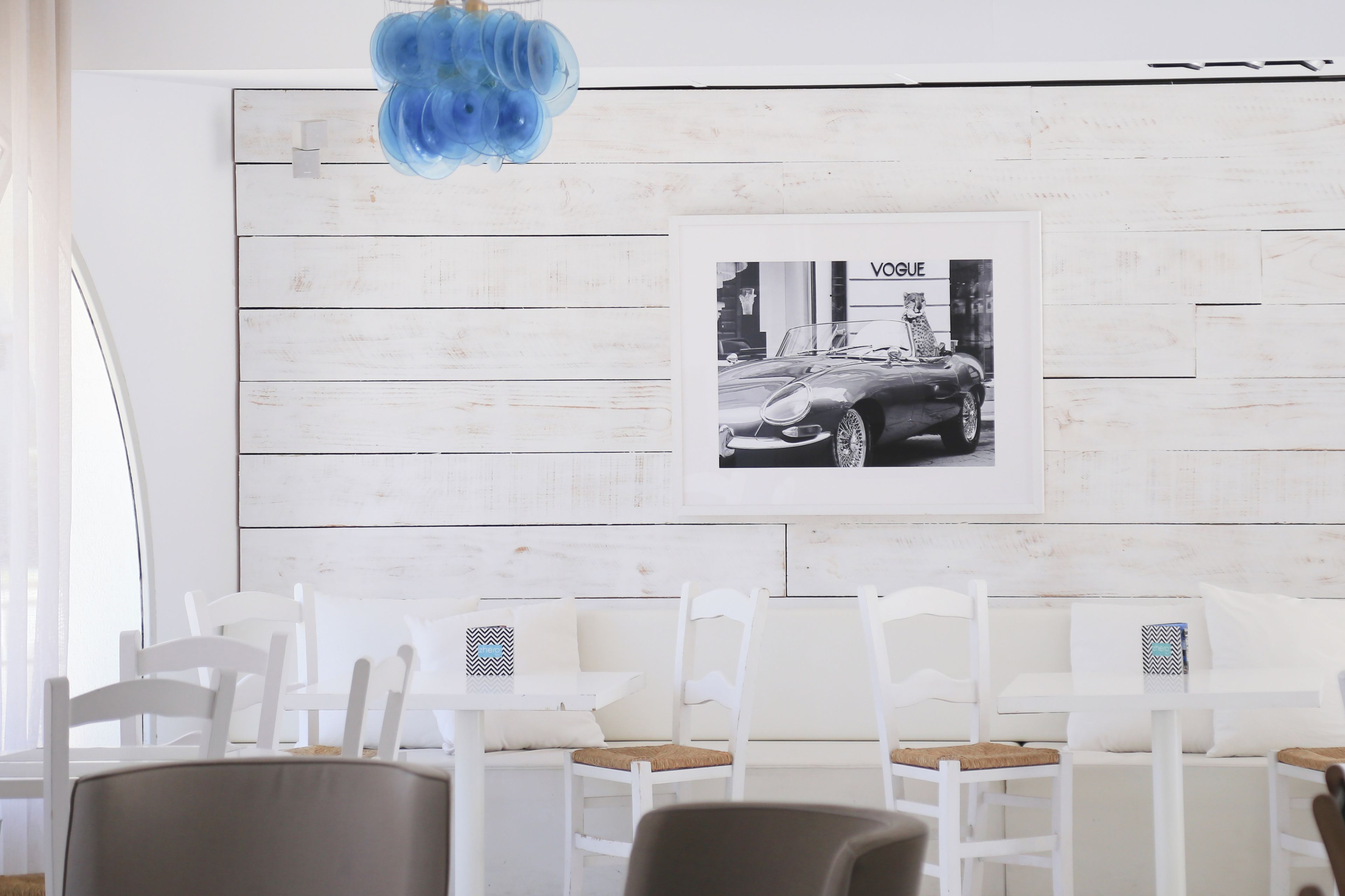 Een moderne kamer met witte meubels, een blauwe hanglamp en een zwart-wit foto in een lijst aan de muur.