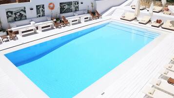 Un área de piscina moderna con sillas de descanso y un deck blanco.