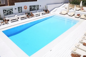 Un área de piscina moderna con sillas de descanso y un deck blanco.