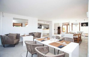 A modern, open-plan living area with a dining table set for four, surrounded by wicker furniture and a neutral color palette. - Hotel Zhero-palma (Calvia)