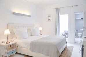 A modern bedroom with a large bed, bedside tables with lamps, a small drawer, a framed picture on the wall, and an open door leading to a bathroom. - Hotel Zhero-palma (Calvia)