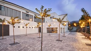 A courtyard with a paved walkway, string lights, and small trees. - Hotel Boutique Molino De Enmedio (Hueneja)