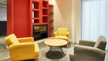 Una sala moderna con una pared de acento roja, un televisor y dos sillones amarillos.