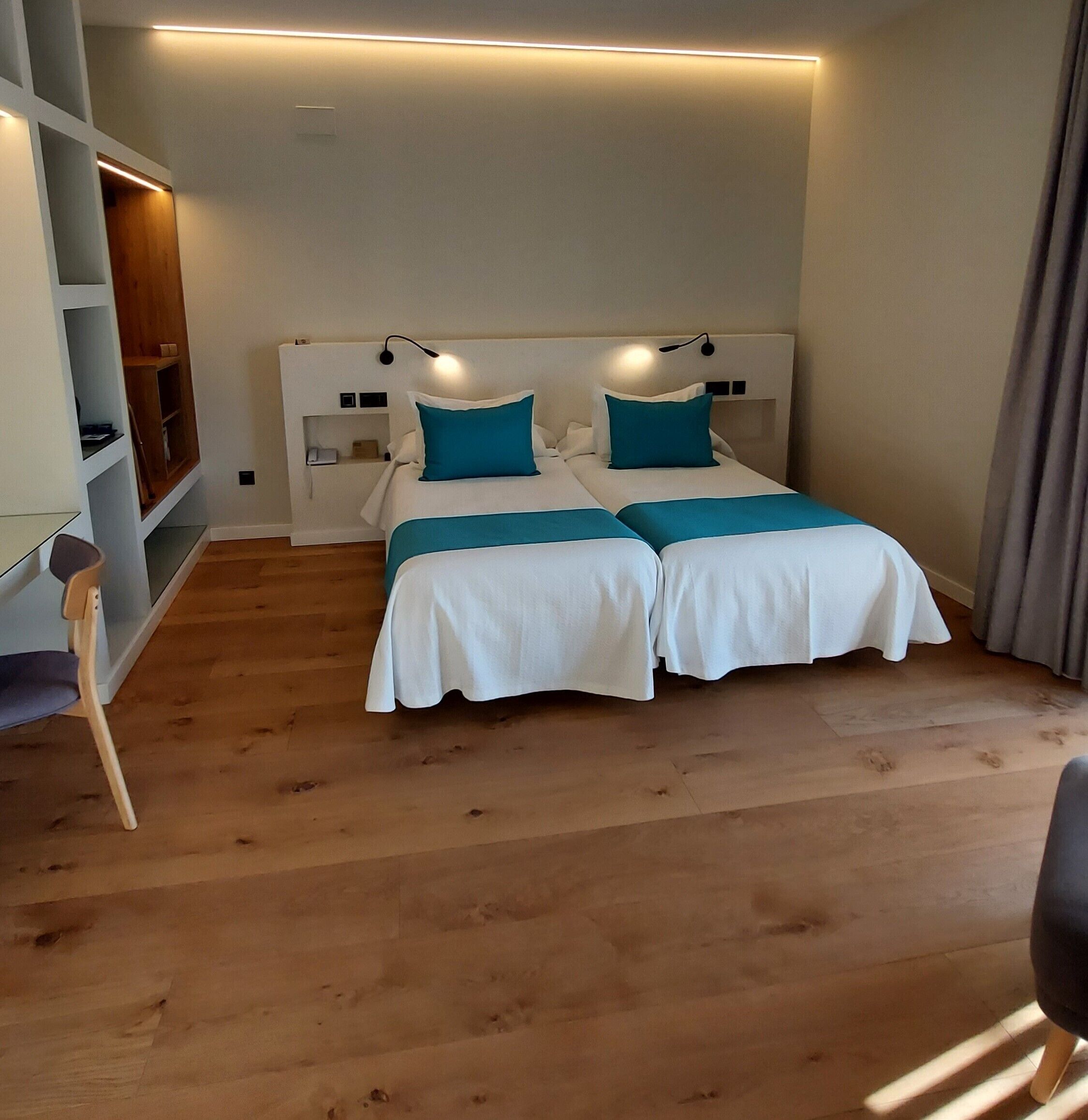 Une chambre avec deux lits, un bureau et une étagère.