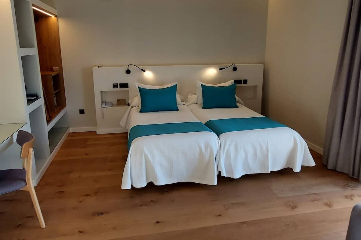 Une chambre avec deux lits, un bureau et une étagère.