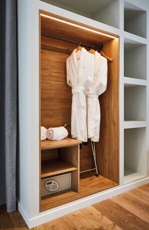 A walk-in closet with wooden shelves, a robe hanging on a rack, and a folded towel on a shelf. - Hotel Boutique Molino De Enmedio (Hueneja)