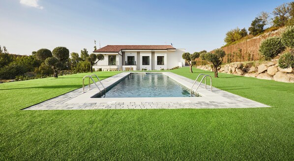 A modern house with a swimming pool, surrounded by well-maintained grass and trees. - Hotel Boutique Molino De Enmedio (Hueneja)