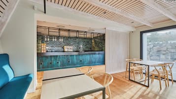 Un interior moderno con una zona de bar, asientos y vistas amplias a través de un ventanal.