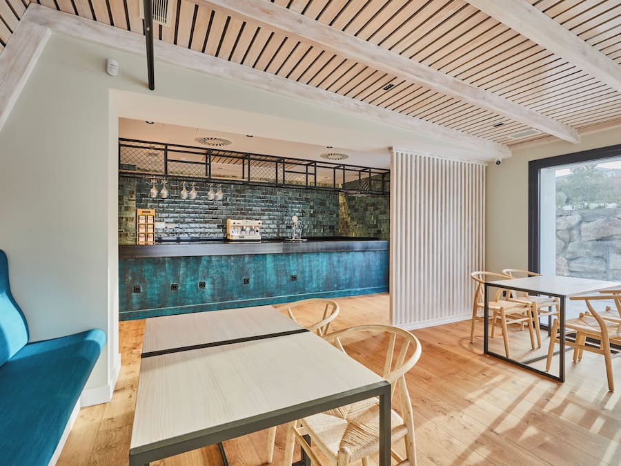 Un interior moderno con una zona de bar, asientos y vistas amplias a través de un ventanal.