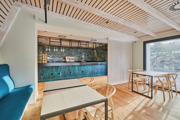A modern interior with a bar area, seating, and a view through a large window. - Hotel Boutique Molino De Enmedio (Hueneja)