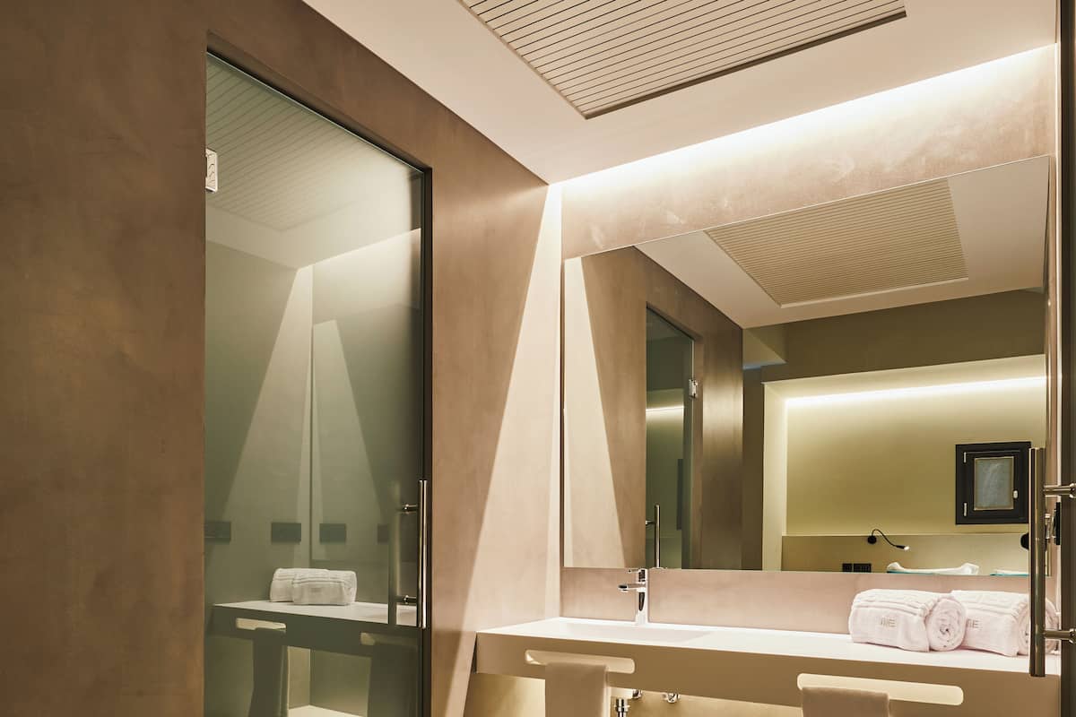 Une salle de bain moderne avec une douche à parois de verre, un grand miroir et un meuble-lavabo doté d’un porte-serviettes.
