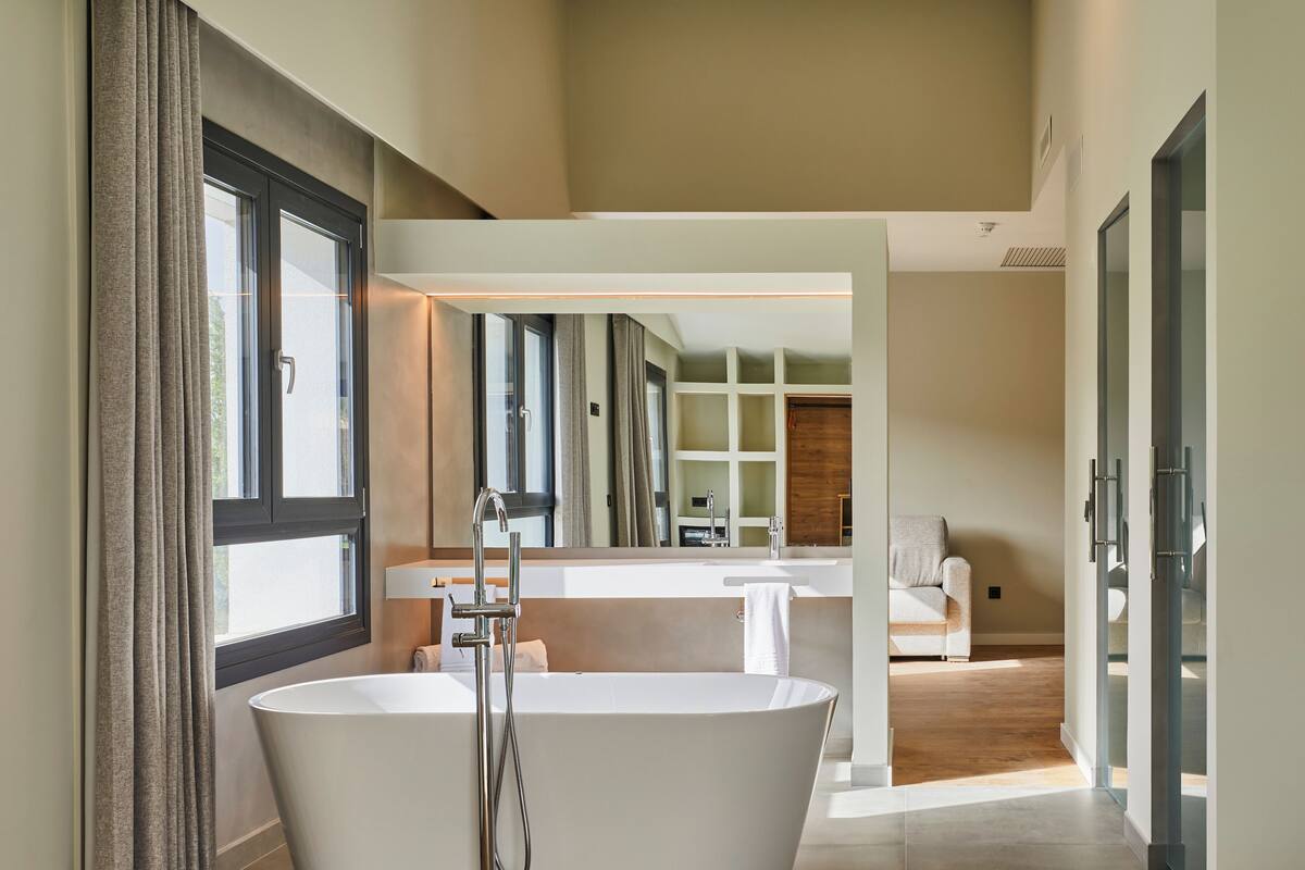 Une salle de bain moderne avec une baignoire sur pieds, un grand miroir et un plancher en bois.