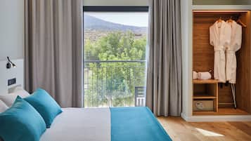 Un dormitorio con cama, armario y balcón con vistas a árboles y colinas.