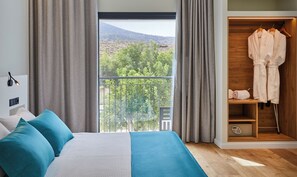 A bedroom with a bed, a wardrobe, and a balcony with a view of trees and hills. - Hotel Boutique Molino De Enmedio (Hueneja)